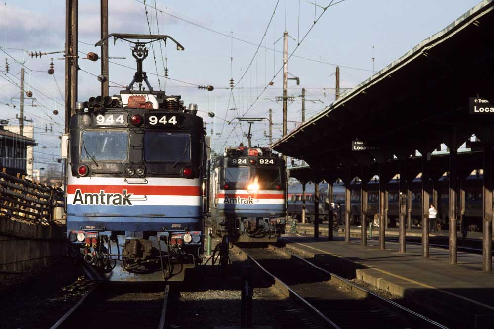 Two electric locomotives with red, white, and blue stripes at station