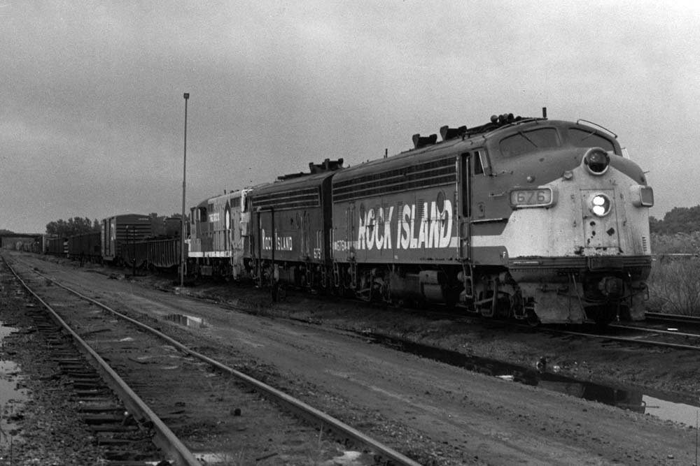 Streamlined diesel locomotive leads freight train through a yard