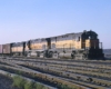 Three diesel locomotives with freight train arriving in yard