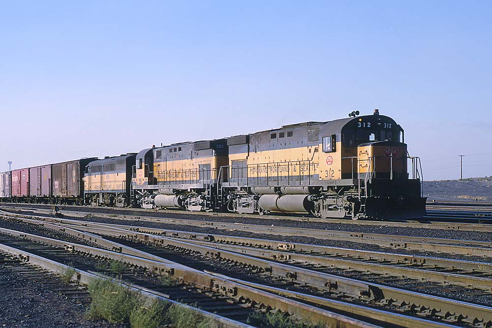 Three diesel locomotives with freight train arriving in yard
