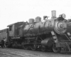 Men standing by steam locomotive tender on passenger train