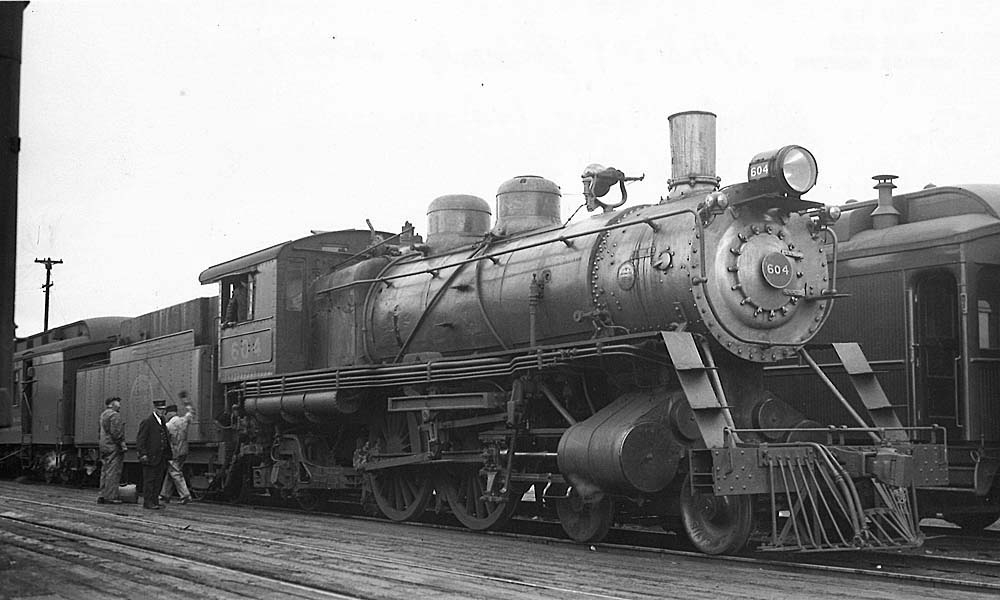 Men standing near a steam locomotive on a passenger train