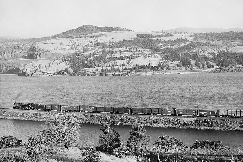 Spokane, Portland and Seattle Railway steam locomotive with freight train on river bank