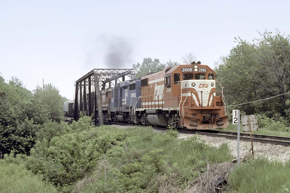 Red-and-white diesel locomotive with freight train on truss bridge
