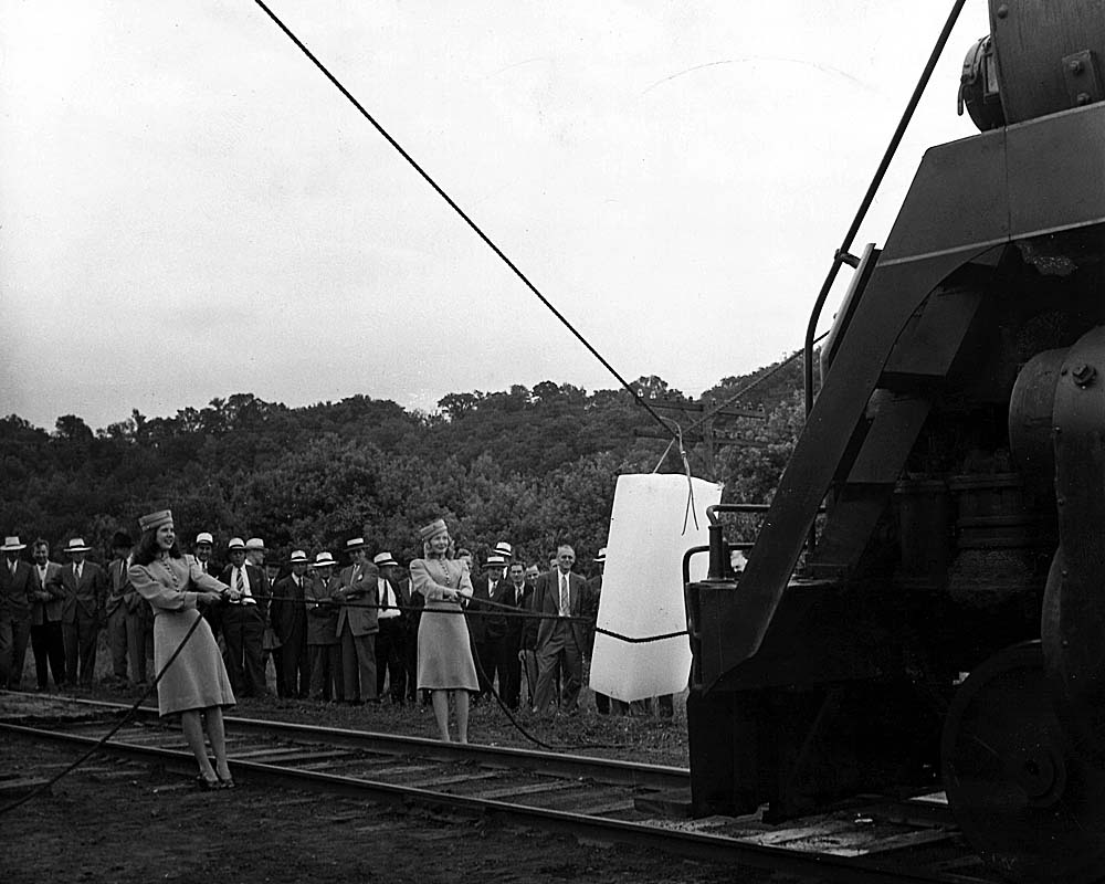 Two women stand in front of a steam locomotive with large ice block