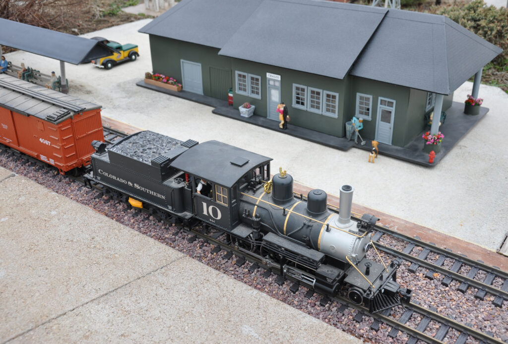model train approaches depot on garden railway