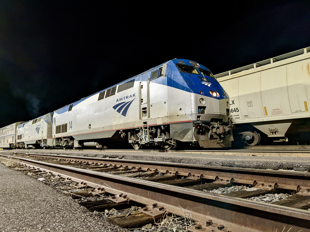 Amtrak diesel engine in front of freight train at night