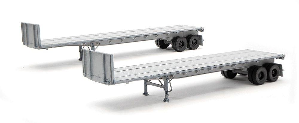 Two gray flatbed semi trailers