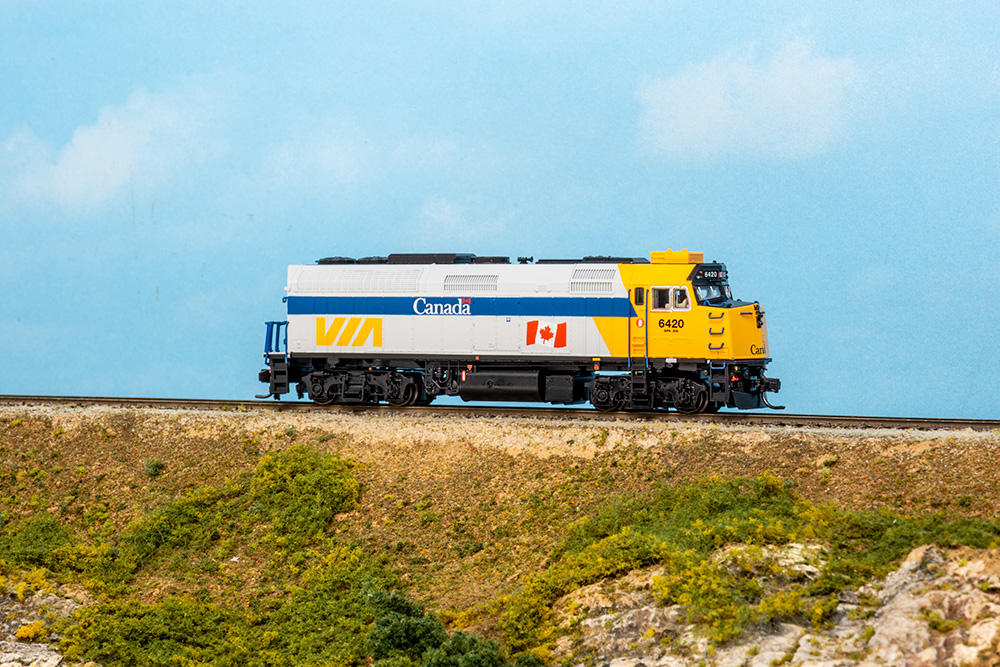 Gray and yellow train locomotive on tracks with a blue sky background