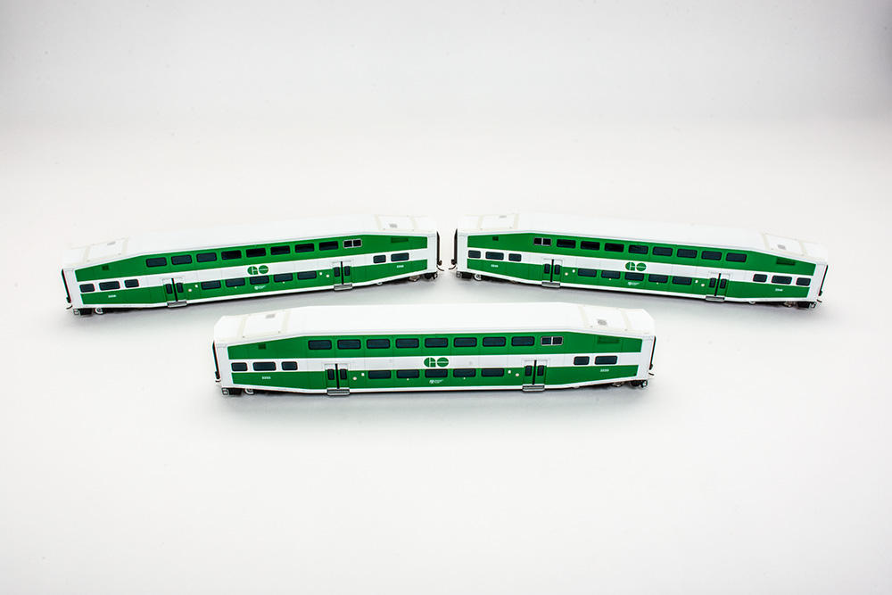 Three green and white bi-level commuter cars