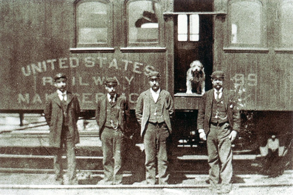 Owney the Post Office dog stands in the door of a railroad mail car