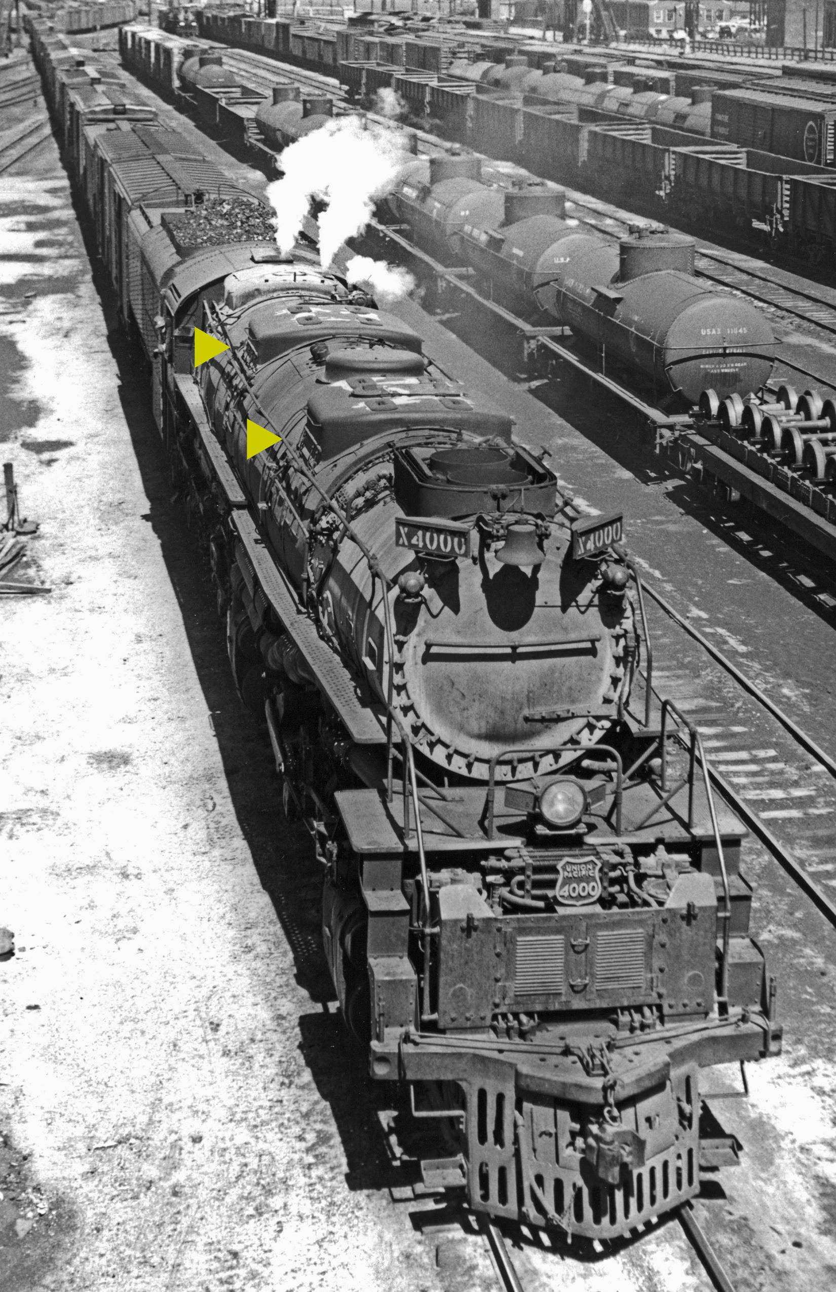 Big Boy locomotive pulling train through freight yard.