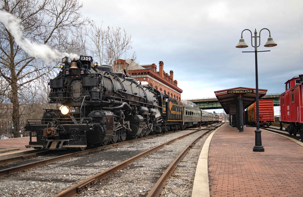 Large steam locomotive with train at station