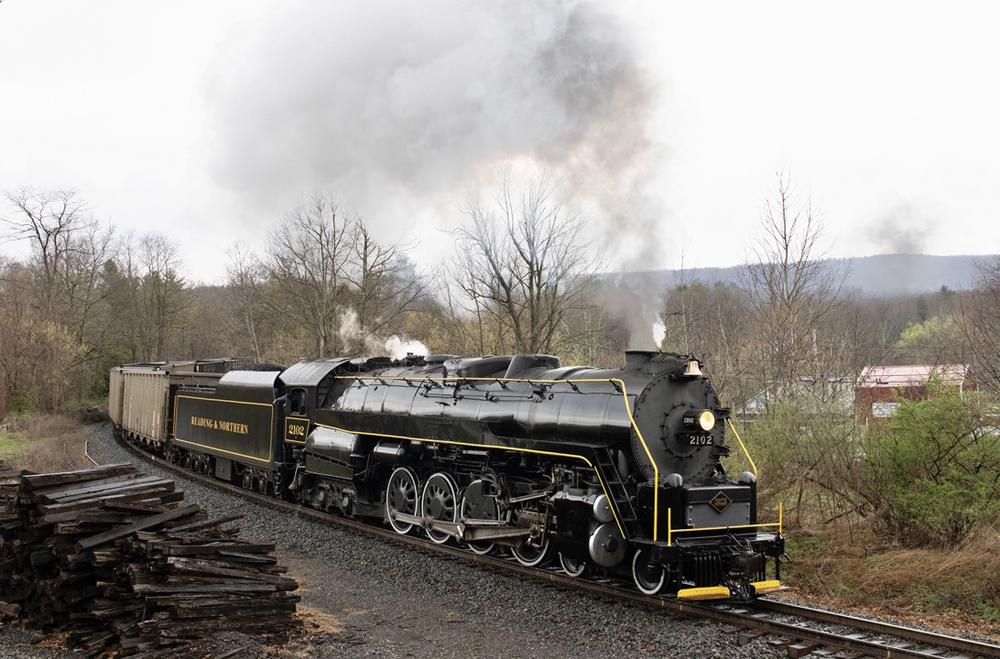 Steam locomotive pulling freight cars rounds curve