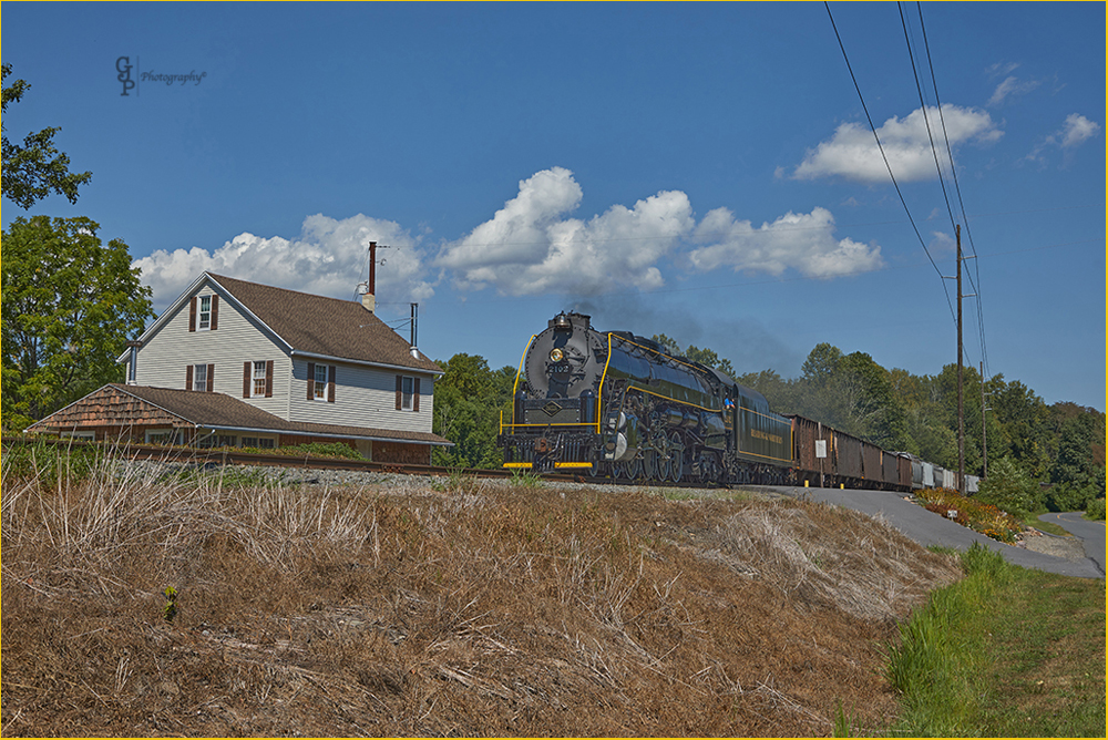 Steam locomotive and freight cars under blue skies