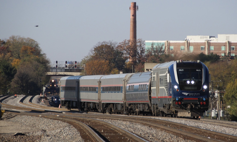 Passenger train rounding curve with another train in background