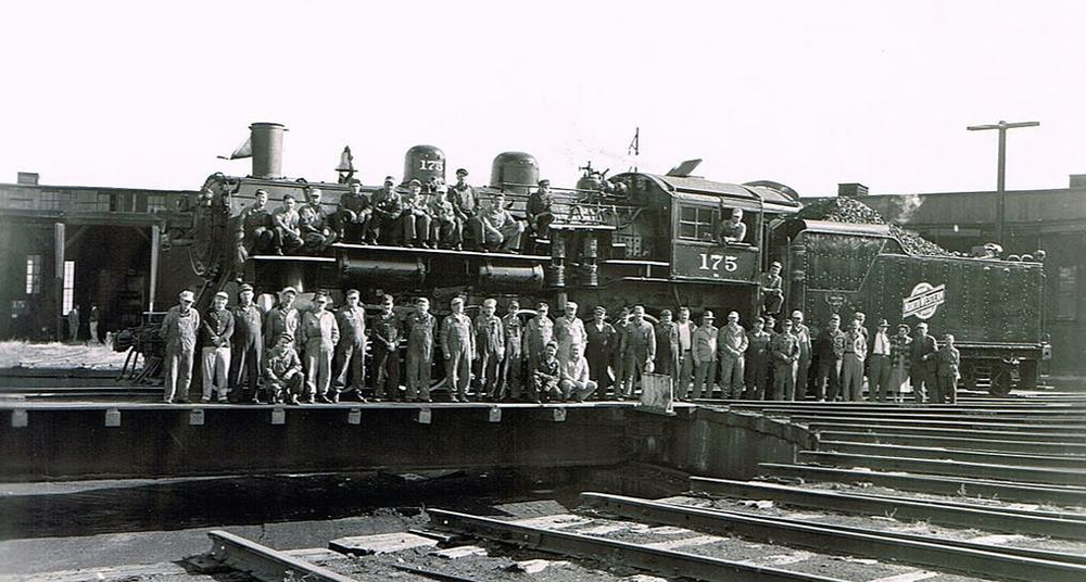 Steam locomotive on turntable with large group of railroaders