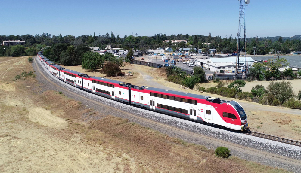 Red and white bilevel commuter train cars round curve