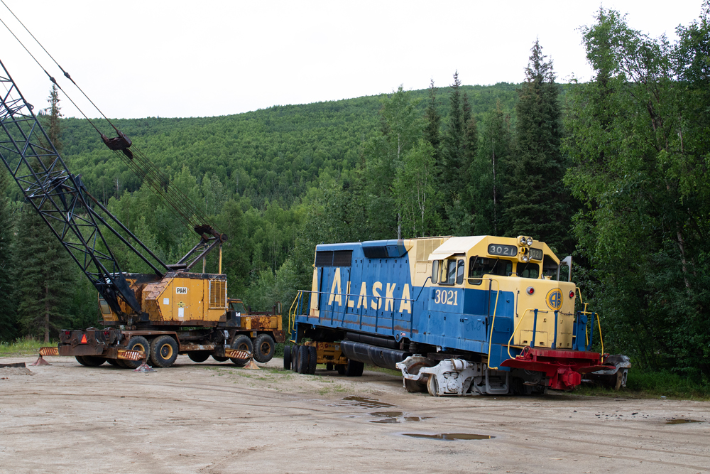 Diesel locomotive and crane on dirt lot