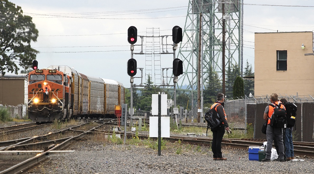 Mean standing near railroad tracks as train approaches