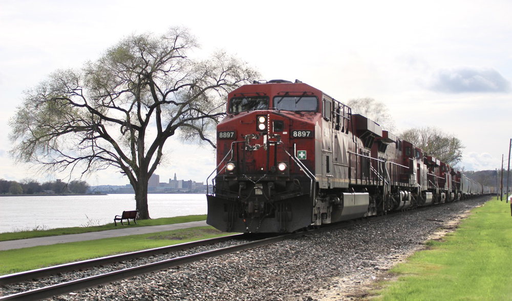 Freight train with red locomotives on tracks near river