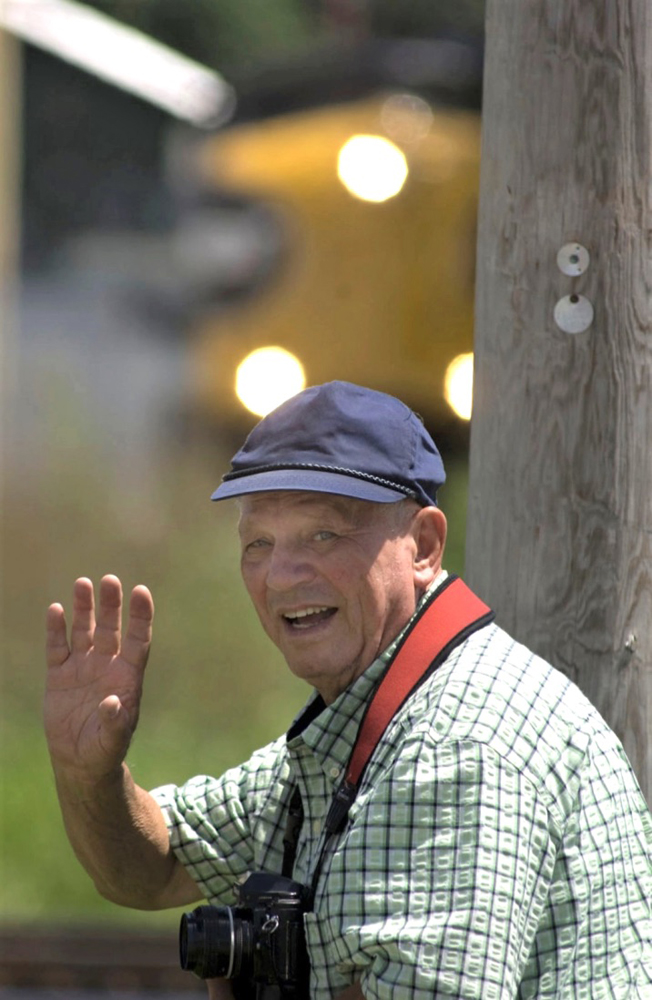 Man with camera waving with train in background