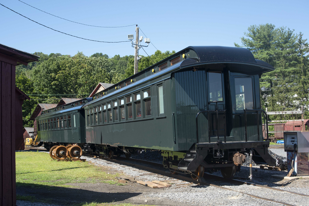 Two dark green passenger cars on siding