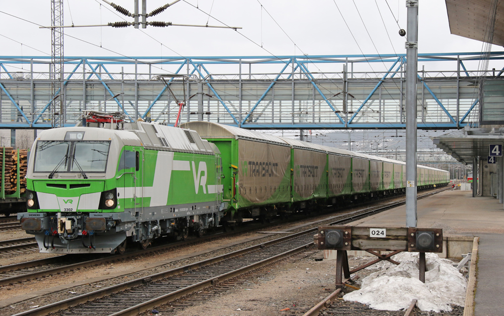 Green and white electric locomotive pulling freight cars