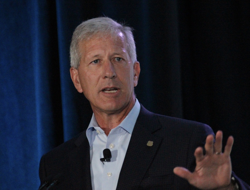 Gray-haired man in blue sportcoat gesturing