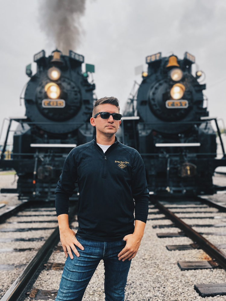 Man standing in front of two steam locomotives