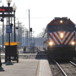 Commuter train arrives at platform with another train stopped on adjacent track