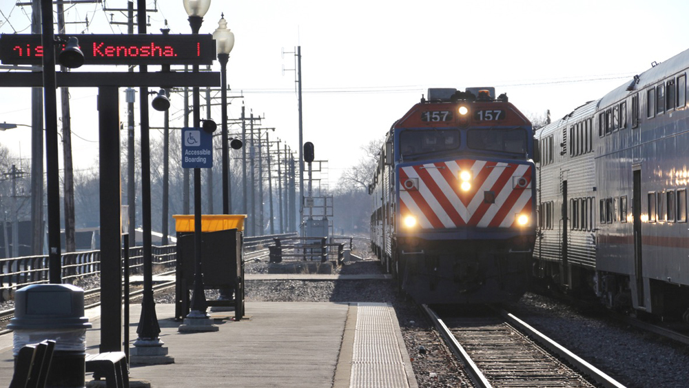 Commuter train arrives at platform with another train stopped on adjacent track