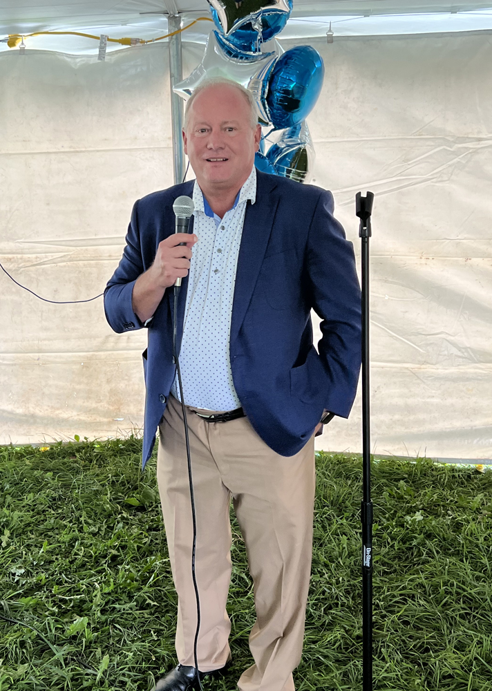 Man in blue blazer speaking into handheld microphone