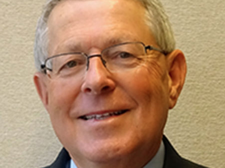 Head shot of smiling man with gray hair and glasses