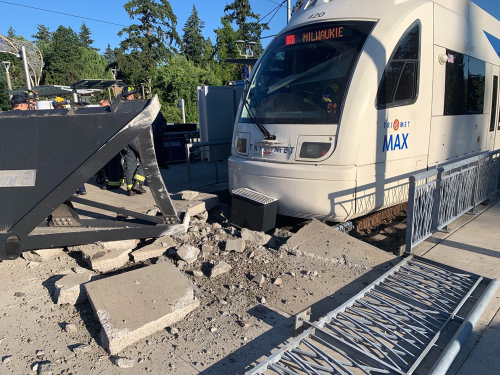 LIght rail train runs through end of track bumper, breaking up concrete sidewalk