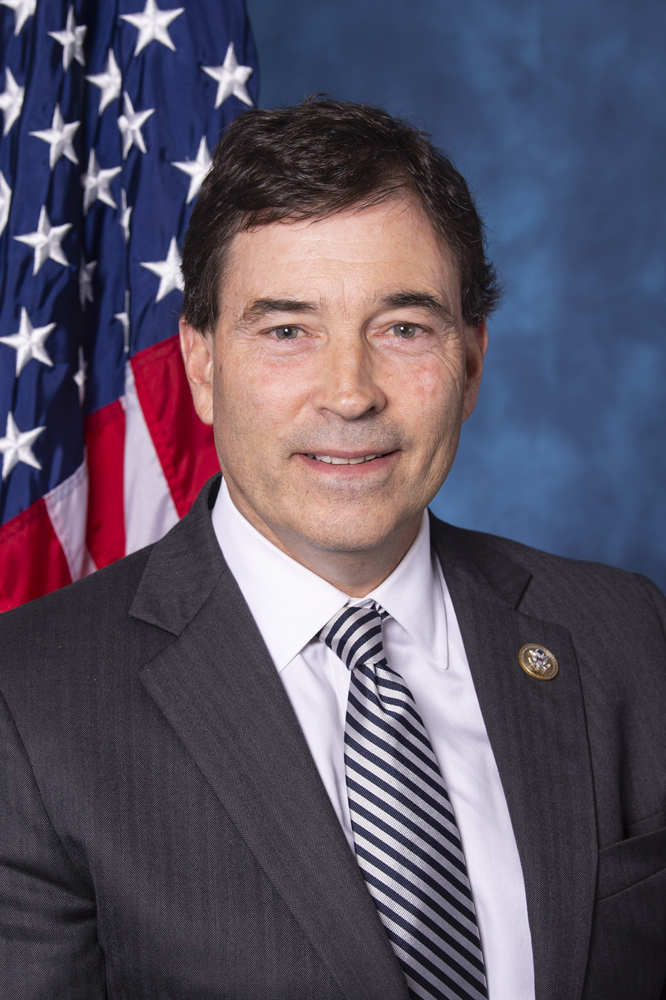 Man in suit standing in front of American flag