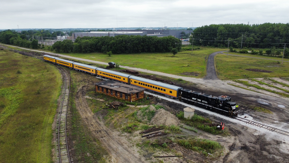 Black locomotive with five yellow passenger cars