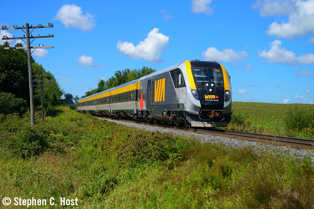 Yellow and gray passenger trian with streamlined locomotive in rural setting