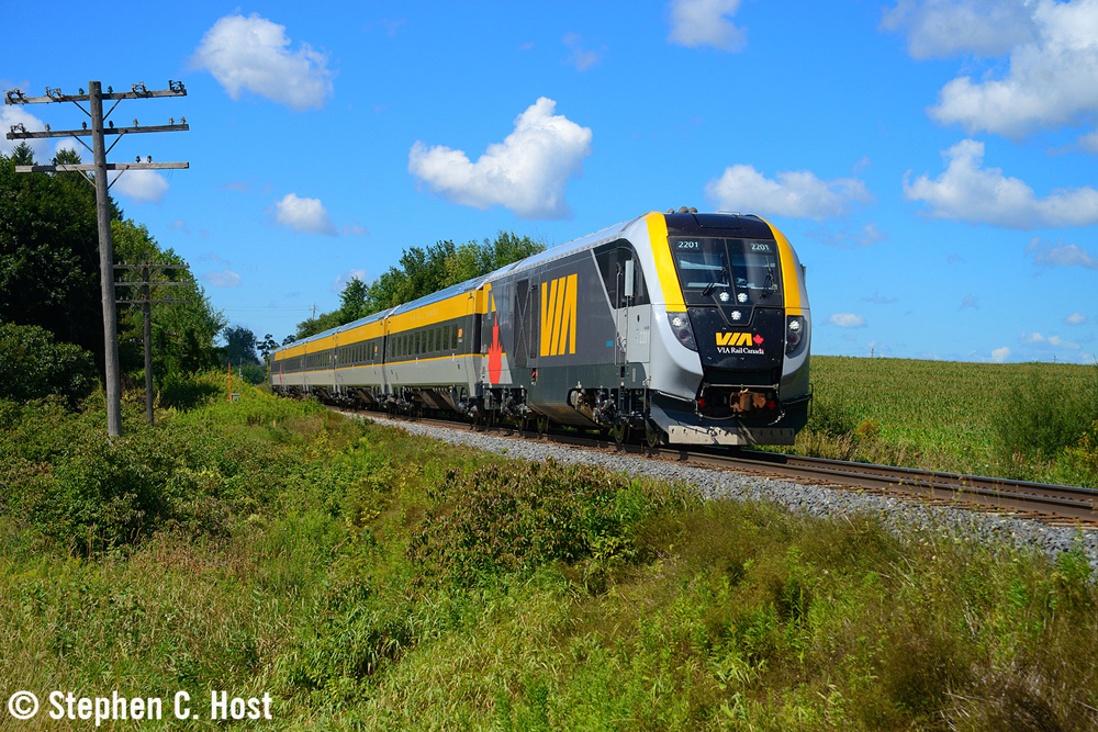Blue, yellow and gray passenger trian with streamlined locomotive in rural setting
