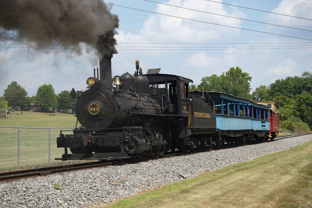 Small steam locomotive with two open-air cars and caboose