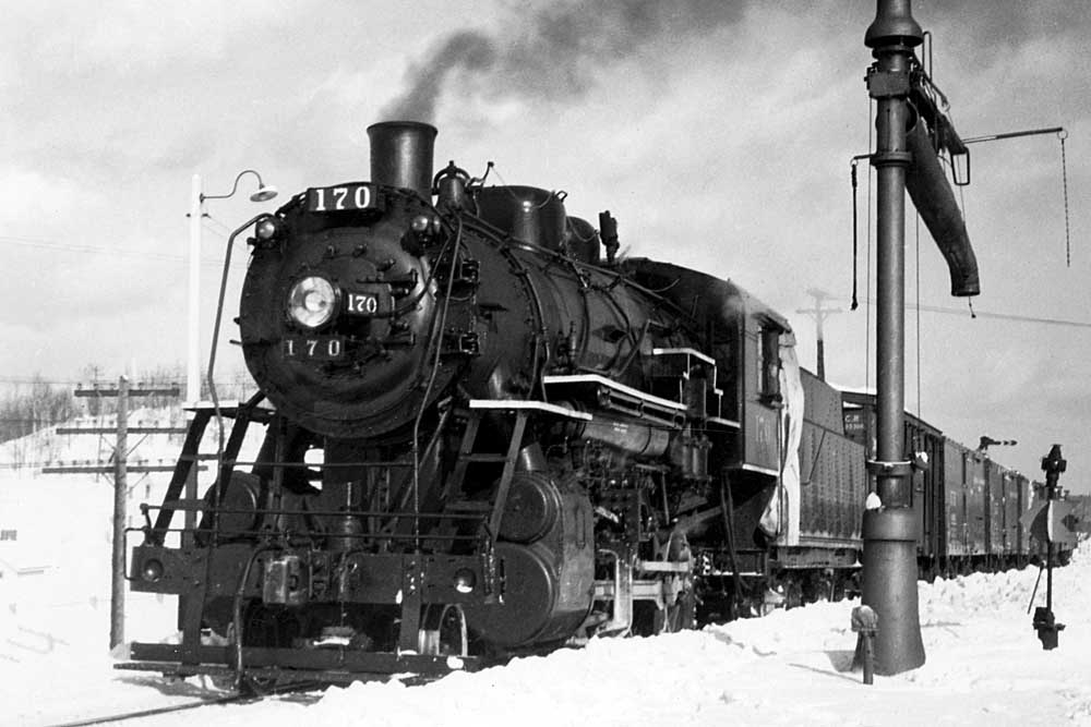 Steam Bangor & Aroostook Railroad locomotive with freight train by water fill spout