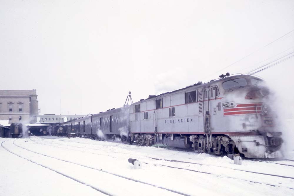Streamlined silver diesel locomotive carrying railroad mail service cars