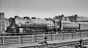 Steam locomotive with passenger train behind railing