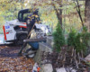 Bobcat with man nearby and piles of debris