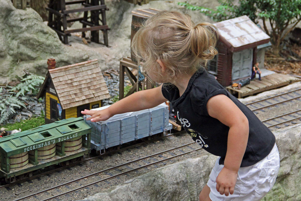 Girl reaches out to touch piece of model rolling stock