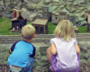 two children watching a model train on a garden railway