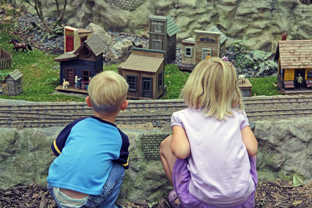 two children watching a model train on a garden railway