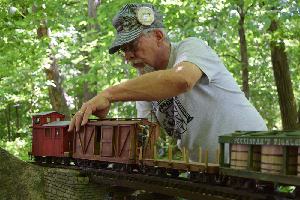 a man with a large-scale train on track