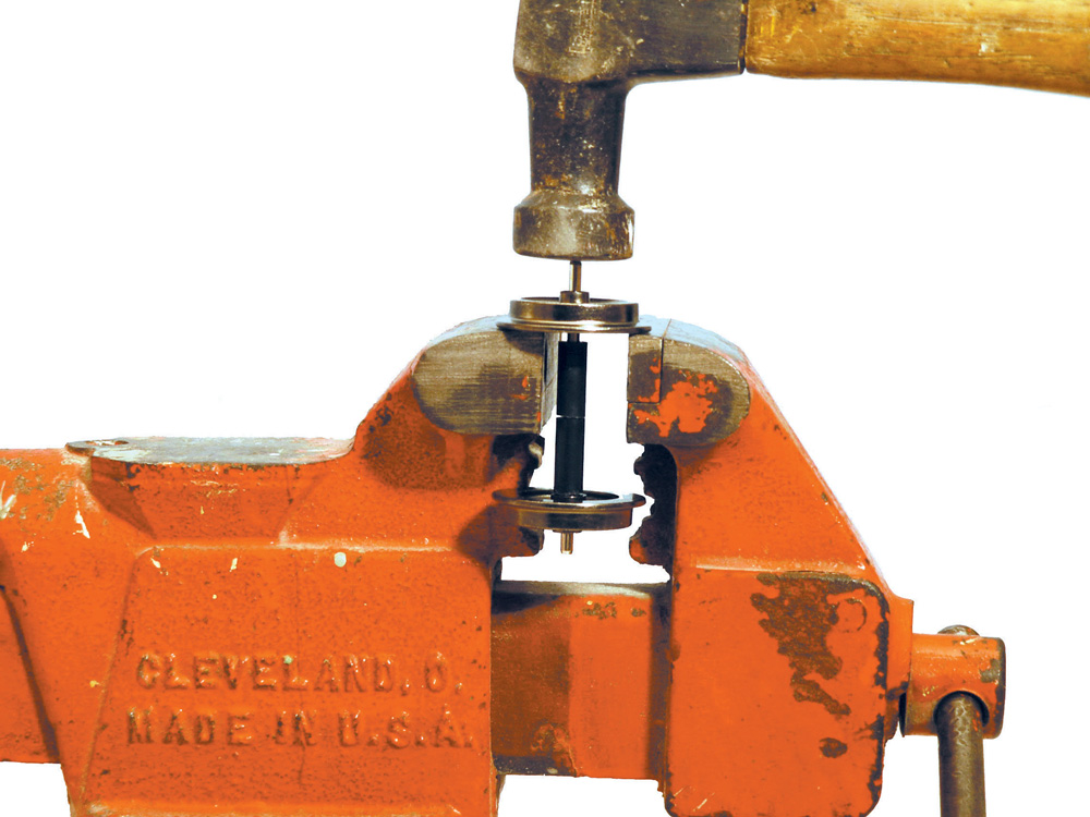 Pair of model locomotive wheels in vice with hammer tapping them