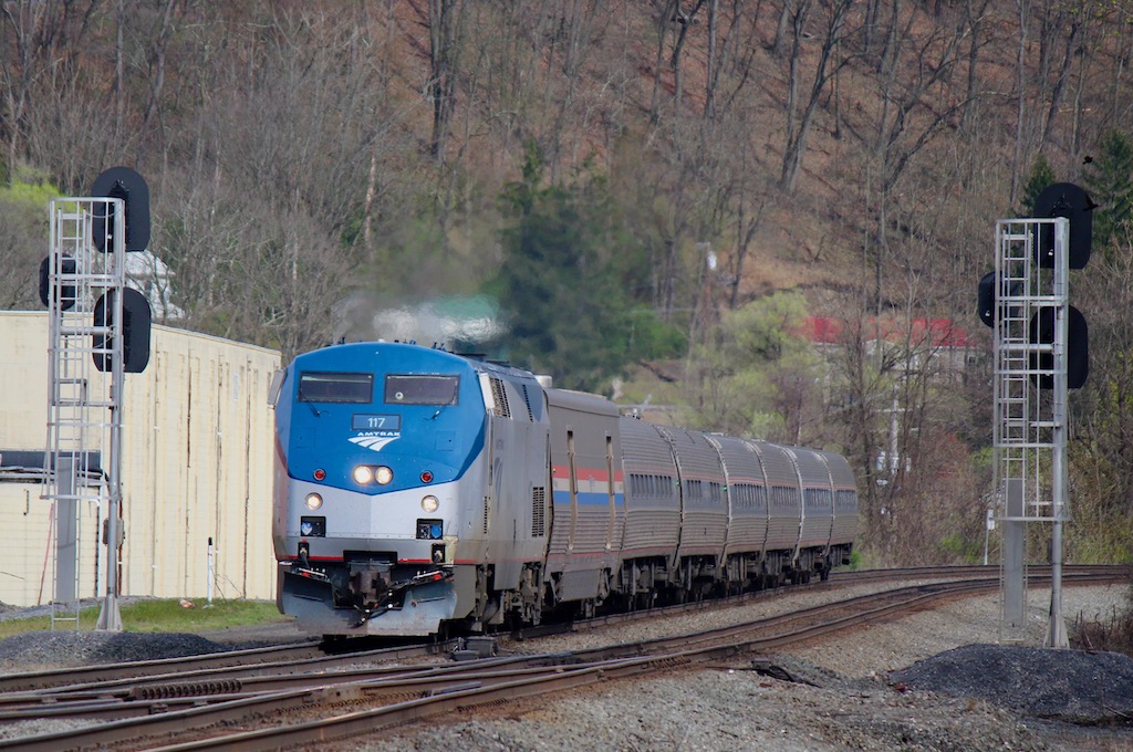 Passenger train with one locomotive and seven cars passes between signals